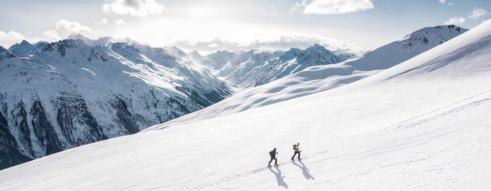 2 people hiking in the snow on skis